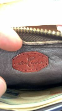 財布のメーカーを教えてもらいたいです。 編み込みデザインの長財布にこのようなマークがあるのですが、なんと書いているか分かりません。また、どこのメーカーの財布でしょうか？