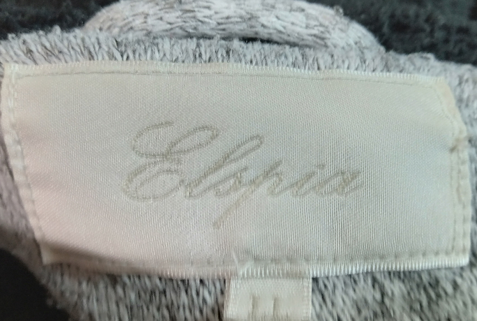 英語の質問をお願いします。 このジャケットのメーカーの名前だと思うのですがなんて書いているのか読めません。 教えて頂けるとありがたいですm(_ _)m