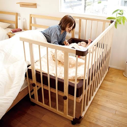 添い寝用ベビーベッドに赤ちゃんをスムーズに寝かせられる方法を教えていただきたいです。 厳密に言えば、添い寝用ではない普通のベビーベッドを、大人のベッドと同じ高さに調整して並べて使っています。添付の画像のような感じです。（設置場所は、大人のベッドと壁の間で動かないよう固定しています。ベビーベッドの大きさは70×120のレギュラーサイズです。） しかし、大人のベッドと接している面しか柵が開かないため、赤ちゃんが授乳や抱っこで寝た後、赤ちゃんを抱えながら大人のベッドの上を「膝で歩いて」ベビーベッドまで運んでいます。 ただでさえ不安定なベットの上を、重たい赤ちゃんを抱えて膝で移動するため、毎回ひっくり返りそうになります。しかもフラフラするため、起こしてしまいます。 短辺（画像で言えば手前の面）も開くタイプにすれば、大人のベッドを経由せずに寝かせることが出来たのに…と、買ってから後悔しています。 開かない方の柵の上から寝かせてみたこともありましたが、赤ちゃんを柵より高い位置まで持ち上げなくてはいけないのでしんどかったです。 いっそ大人のベッドから離して使おうかなとも思ったのですが、やはり寝ながら常に顔を確認したいし、夜中に泣いた時にすぐ手を伸ばせる方がありがたいので併設はしたいです。 ちなみに、こんな状態でまともに寝かしつけも出来なかったため、子が４ヶ月過ぎる現在まではベッドインベッドを使い、大人のベッドで添い寝しています。（ベビーベッドはオムツ替え台状態……） しかし、だんだん動き回りそうになってきたため、柵のあるベビーベッドに移行していかなきゃな…と思っている次第です。 皆様はどのように寝かしつけされておりますでしょうか？馬鹿な質問で大変お恥ずかしいのですが、なにとぞよろしくお願いいたします。 ここまで読んでいただきありがとうございました。