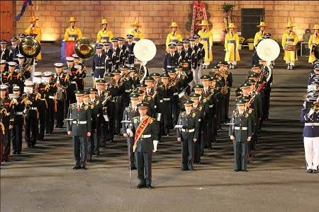 自衛隊の音楽隊で行進するときに、列の前で赤いたすきみたいなものを肩からかけて棒を動かしている人はどのような役割なのですか？ 画像の前の方です