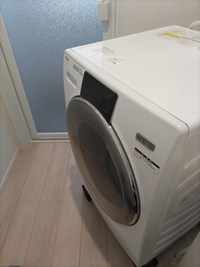 AQUAのドラム式洗濯機を一週間前に購入しました。設置した日からすすぎと脱水時の揺れが激しく、洗濯機が前に歩いてきます。 新しい洗濯機の前に使っていた洗濯機台が高さがあるので揺れるのではということで、電気屋さんで防振防音用のゴムの足を購入して設置し直してもらいましたが、変わらず歩いてきます。重いので一人で元の場所には戻せず、困っています。ドラム式洗濯機をお使いの方、こんなに揺れますか？何か対...