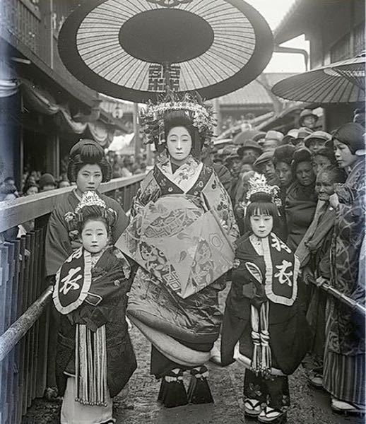 写真の昔の花魁道中の様子で、脇に少し小汚い人達が写っていますがこ 
