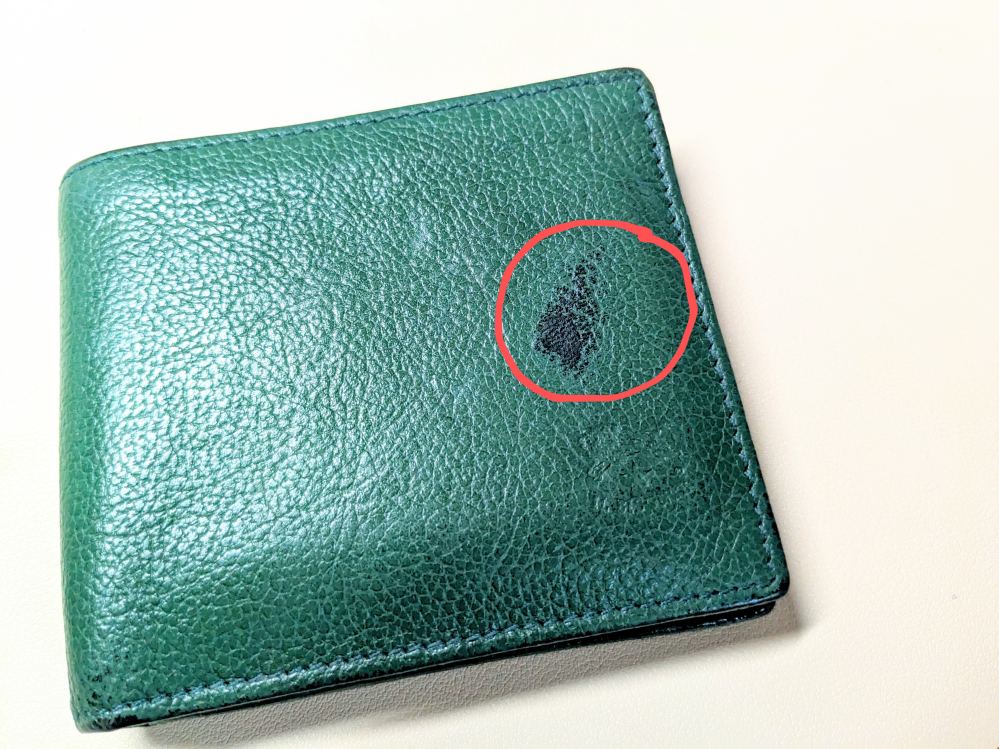 革財布に黒くなっている部分があるのですが、これは傷が変色したのでしょうか？ また、目立たくする方法はありますか？