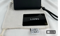 LOEWEの見分け方について。

メルカリでLOEWEの財布を購入しようと思っているのですが、この写真に写っている黒いカードは正規品には存在しないというネットの記事を見ました。 出品者の方はマドリッドのブランドショップで購入されたとのことですが、やはり偽物の可能性が高いでしょうか？