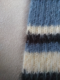 編み物初心者です。 二目ゴム編みでボーダーのマフラーを編んでいるのですが、画像のように糸を変えた部分の左端が全て次の色と少し重なっていることに今気付きました。
白地の部分は余りにも目立つのですが、何か編み方がおかしいのでしょうか？
ひっくり返す時に裏目や表面には気を付けているのですが‥。
こんなものなのでしょうか‥？