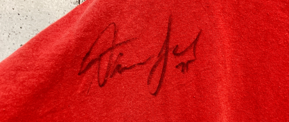誰のサインかわかりますか？ NFLのTシャツを古着屋で買ったのですが、よくみたら誰かのサインがついていました。 どこかのプロ選手のものでしょうか？詳しいかたいますか？？