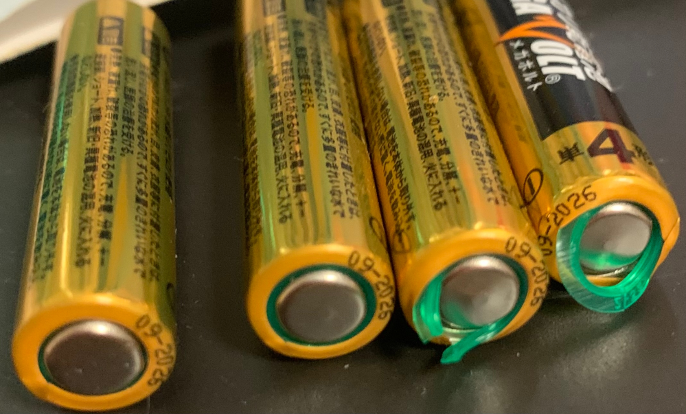 乾電池について。 (アルカリ乾電池メガボルト単4電池) ダイソーの光るミラーに、画像の乾電池4本を使用していたら 突然乾電池のフタが取れていて中身を見たら 2本だけ緑の輪が出てきていました。 これは使用しない方が良いですか？ そしてこれが何かと、なぜ4本中2本なのか わかる方教えていただけると助かります。