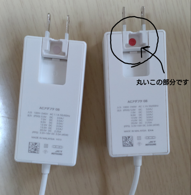 ドコモ充電器のACアダプタ08をウエットシートで拭いていたところ、コンセントの裏側部分にあった丸い白い接着が剥がれて赤色が出てきました。 これは剥がれた状態で使っても問題はないんでしょうか？ とても心配です…。 詳しい方いらっしゃいましたら教えて下さい。 画像右側の部分が赤く剥がれました。 左側は同じタイプの充電器を家族から借りています。