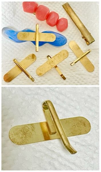 ハンドメイド・アクセサリー作りで使う 金具やパーツについて 【画像あり】 アクセサリー作りのために購入した金属製の金具やパーツのほとんどに手垢のような汚れやくすみがあり、困っています。 ①汚れを落とす方法はありますか？ ②汚れているパーツの使い道は何かないでしょうか？色を付けたレジンを塗ったら汚れがわからなくなるなど… ③金属製のパーツの中では汚れや変色しにくい方な素材はありますか？ ④金属製のパーツのオススメや、注意点などあればアドバイスください。 画像はヘアクリップとポニーフックのパーツです。 素材はおそらくアルミ合金やスチール。 色はKCゴールド。 手垢のような汚れで錆ではありません。 中性洗剤を薄めたぬるま湯で洗ったり、 除菌アルコールスプレーとクロス拭きをしましたか汚れは落ちませんでした。 ①〜④のどれかだけでもご回答いただけると有り難いです。よろしくお願いいたします。 長文、読んでいただきありがとうございます。