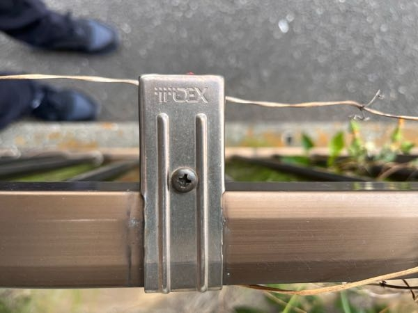 アパートの敷地を囲むように、コンクリートブロックにたてているフェンスのメーカーを探しています。 フェンスを支えている部品に、写真の様な刻印があるのですがわ何と言うメーカーでしょうか？