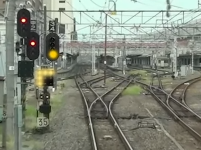 鉄道（主にJR）の信号について質問です。 写真の注意信号の下に、９つのランプが四角く並んだ信号があるかと思いますが、 くの字に左上を指しています。しかし、レールの分岐状態を見ると右方向への分岐です。 くの字はなぜ右上を指さないのですか？ ●●● 〇〇● 〇〇● また、この９つのランプが四角く並んだ信号の名前があれば教えてください。